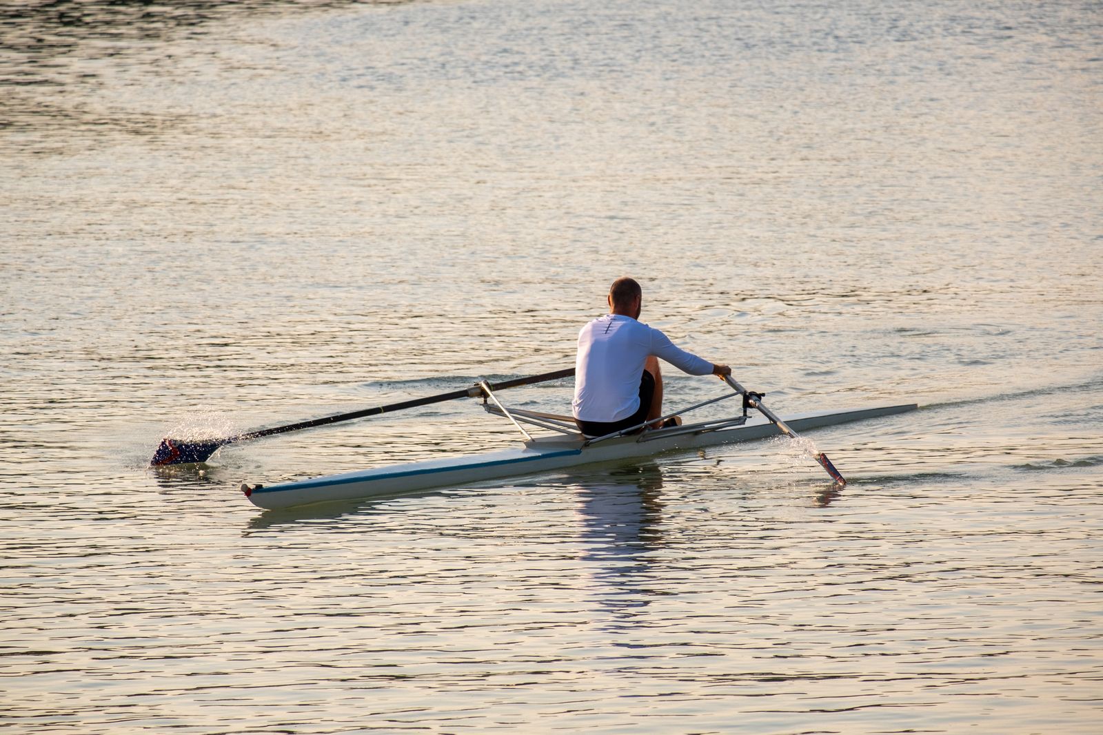 A rower training on the water at sunset